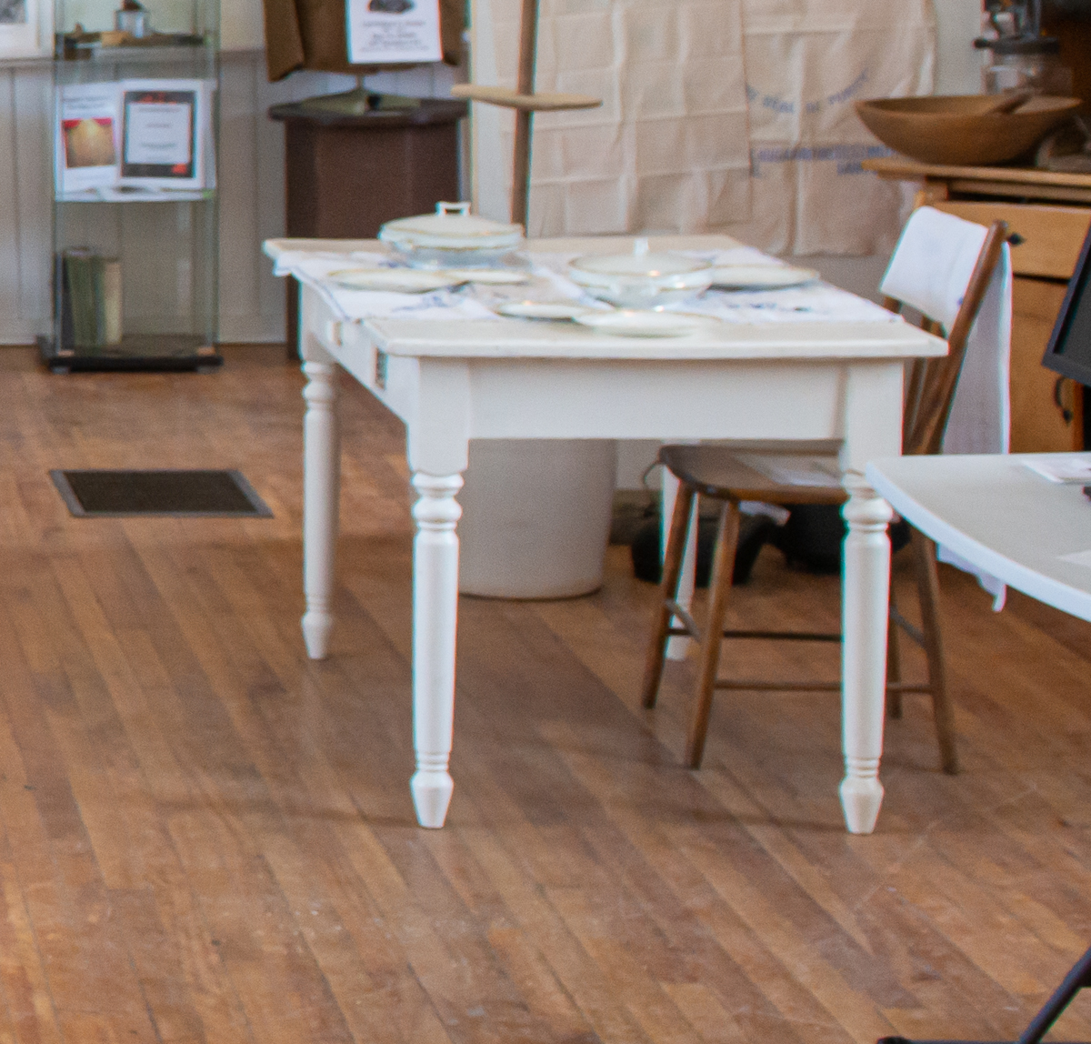 White wooden table set for dining on wooden floor.