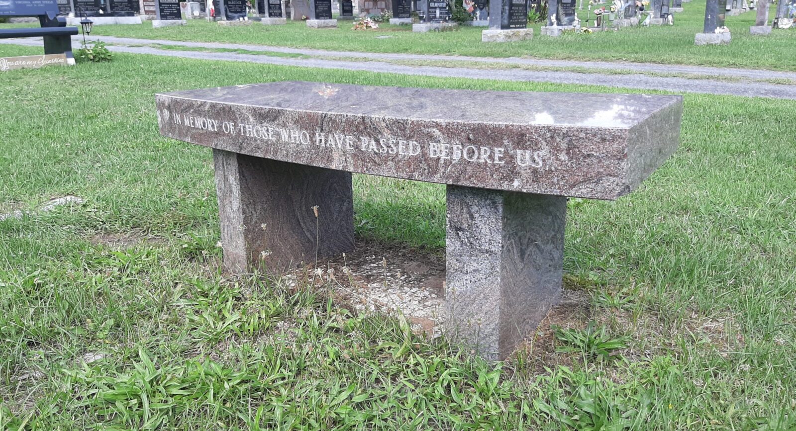 Stone bench in a cemetery setting.